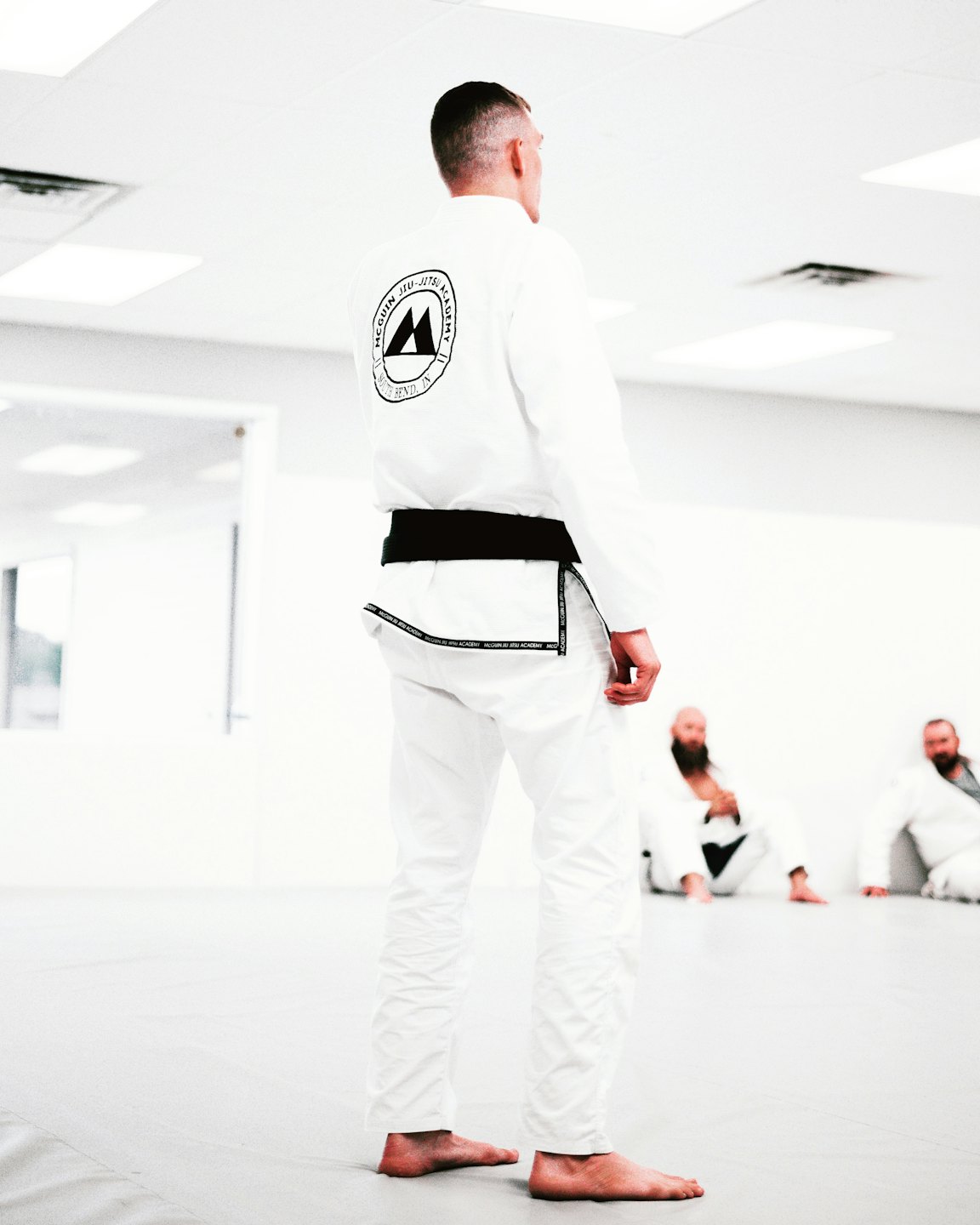 Martial artist in white gi with black belt in a dojo.