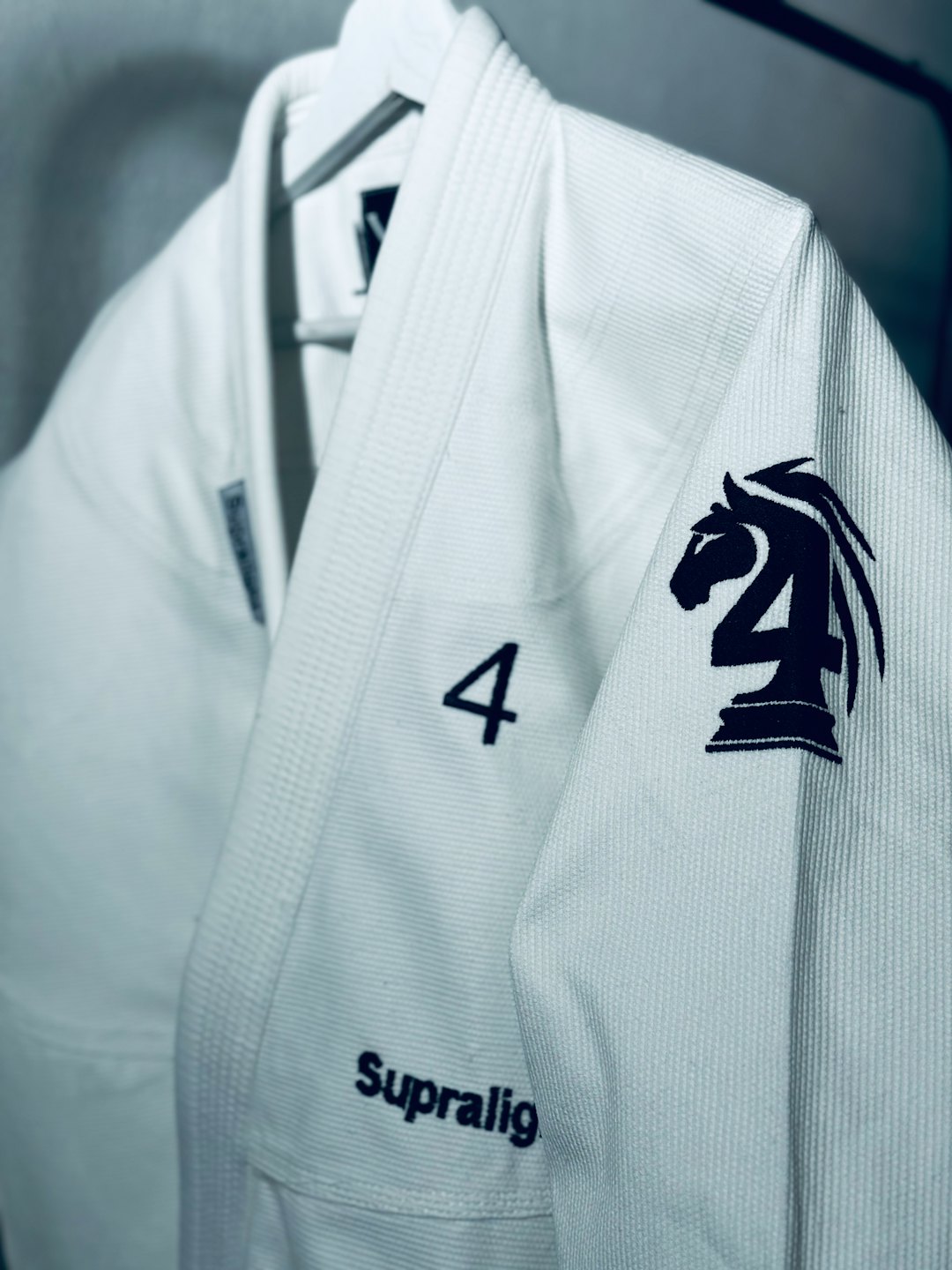 White martial arts gi with embroidered '4' and knight logo.